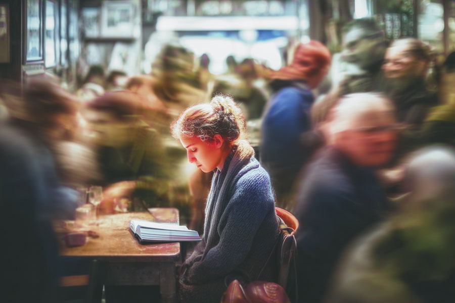 A person sitting alone in a very crowded cafe
